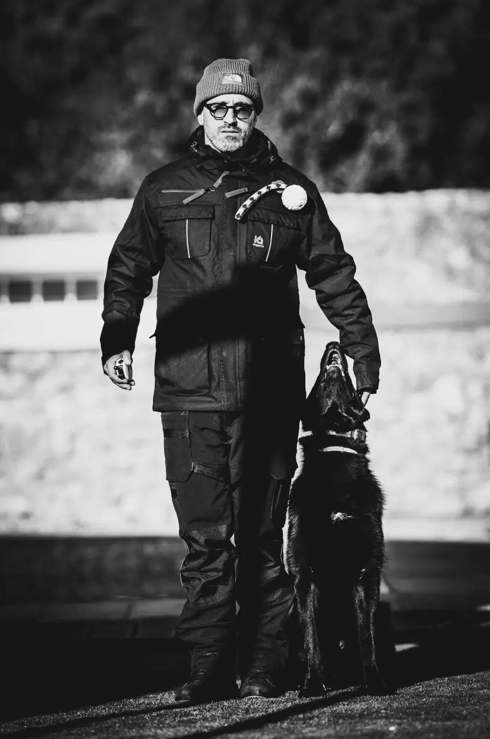 Treinador de pé com um cão preto sentado ao seu lado